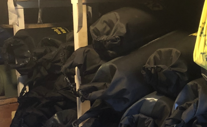 Många fullpackade svarta drybag ligger i en hylla. De innehåller ett liggunderlag, en sovsäck och ett sovsäckslakan.